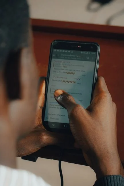 about-01 Hands using smartphone beside laptop with stock charts, showcasing digital trading.